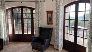 Une pièce avec un fauteuil en cuir noir, de grandes fenêtres en arc de cercle et un tableau accroché au mur.