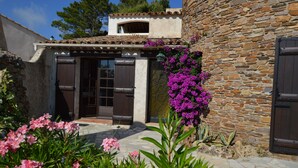 Un bâtiment en pierre avec un toit en tuiles, une porte en bois et une fenêtre.