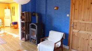 A room with a fireplace, a wooden door, and a chair. - Quietly located cozy vacation home with a view, sauna and wood-burning stove (Ruda)