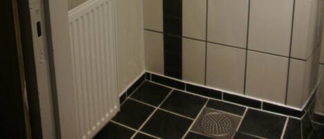 Et badeværelse med hvide fliser, en lodret sort stribe og en hvid radiator.