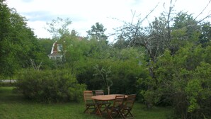 A wooden table and chairs set in a grassy area surrounded by dense foliage. - Quietly located cozy vacation home with a view, sauna and wood-burning stove (Ruda)