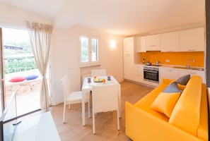 Een lichte keuken met witte kasten en een eethoek met een witte tafel en stoelen.