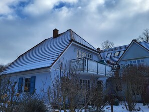 A house with a sloped roof, a visible chimney, and a balcony.