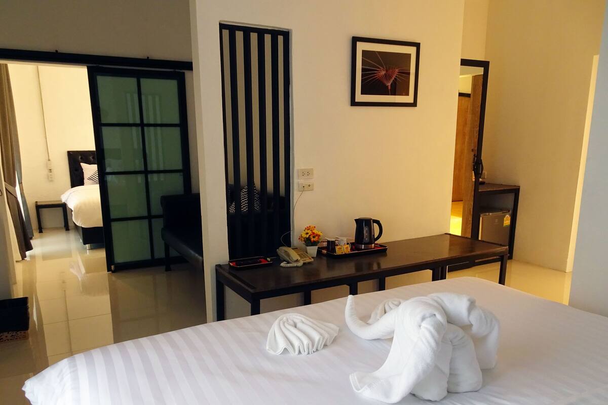 A hotel room with a bed, a desk with a telephone, a coffee maker, and a framed picture on the wall.