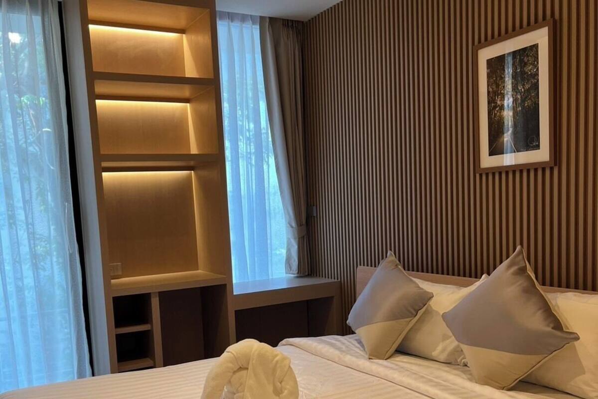 A hotel room with a neatly made bed, a built-in shelf unit, and a framed picture on the wall.