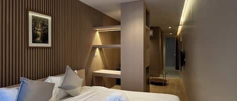 Una habitación de hotel moderna con una cama grande, una mesita de noche, un espejo y un televisor de pared.