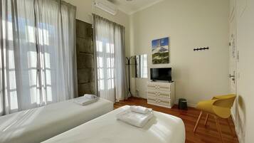Habitación de hotel con dos camas, un televisor, perchero y una silla.
