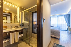 Une salle de bain moderne avec une douche à parois de verre, un meuble-lavabo avec un miroir et un porte-serviettes apparent.
