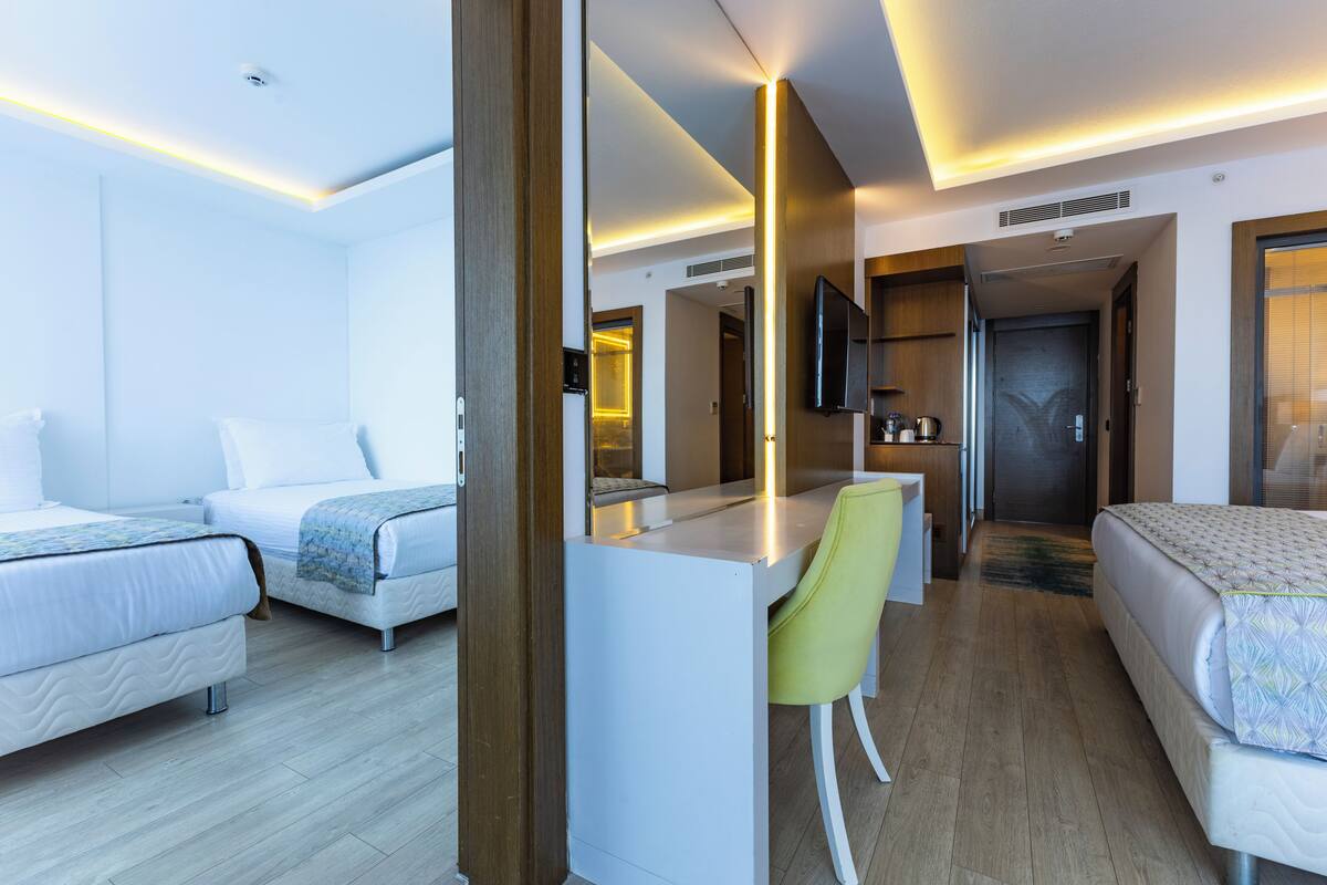 Ein Hotelzimmer mit zwei Betten, einem Schreibtisch, einem Stuhl und einem Fernseher.