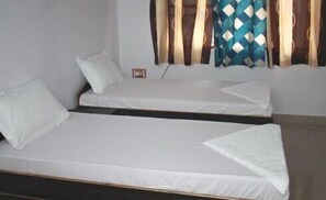 A room with two single beds, white bedding, and a window with patterned curtains. - Hotel Ankur (Patna)