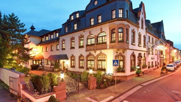 A historic building with a corner turret, large windows, and a well-lit entrance. - Hotel Eurener Hof (Trier)