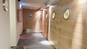A hallway with wooden paneling, a clock, and a sauna sign. - Hotel Eurener Hof (Trier)