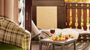 A cozy outdoor seating area with a table set for a meal, a drink, and a view of autumn foliage. - Hotel Eurener Hof (Trier)