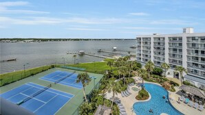 Un resort con cancha de tenis, piscina y vistas al agua.