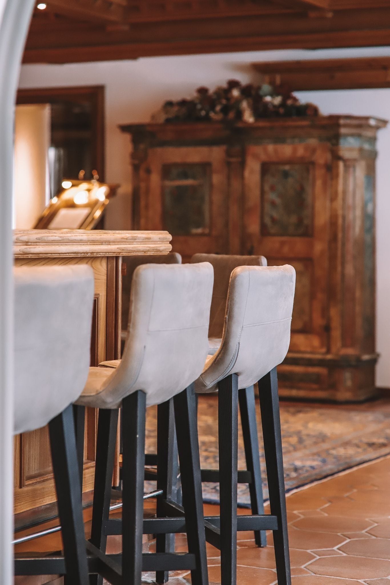 A bar area with high stools and a wooden cabinet in the background.