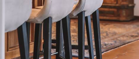 A bar area with high stools and a wooden cabinet in the background.