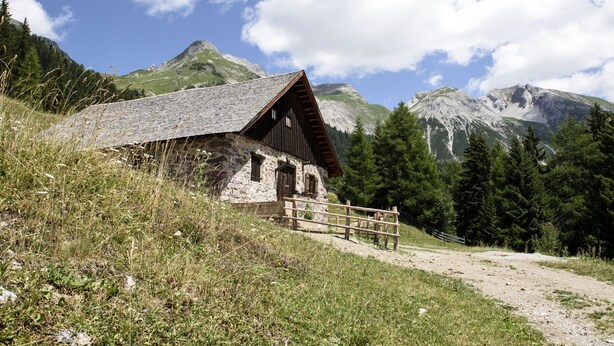 A rustic mountain cabin with a wooden exterior, a stone foundation, and a wooden fence in front. - Hotel Grieshof (Sankt Anton am Arlberg)