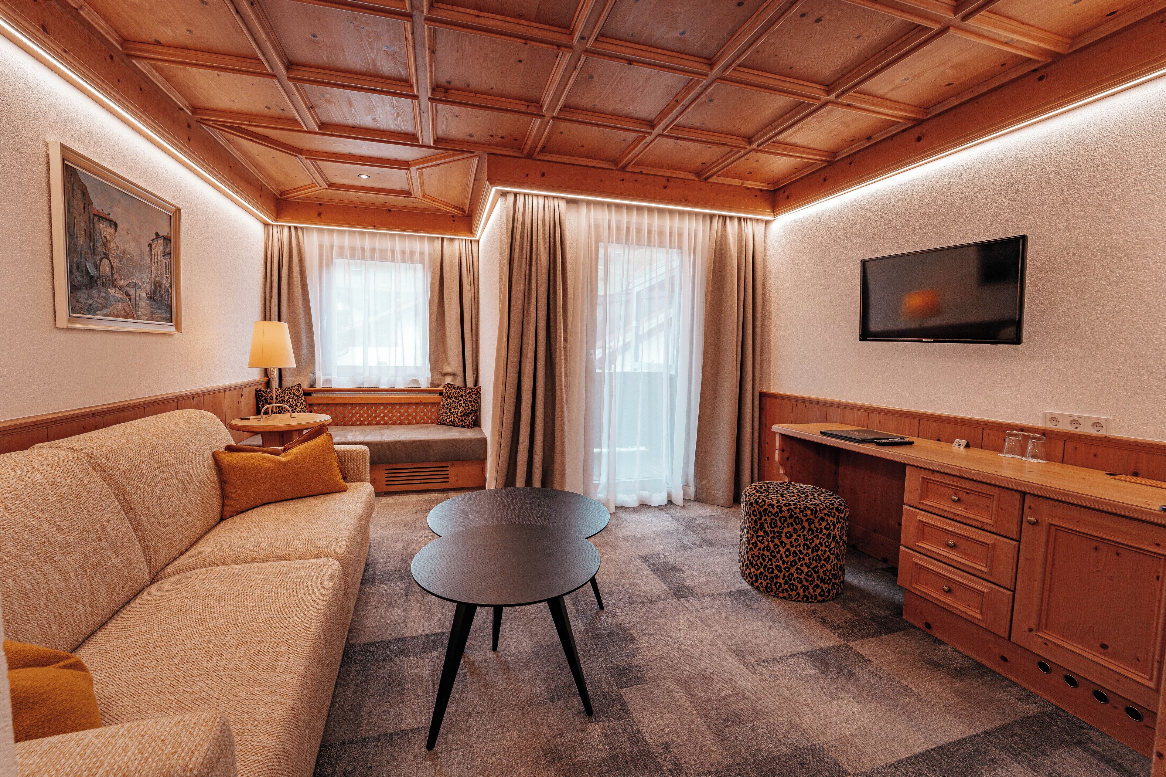 A cozy room with a sofa, a small round table, a television, and a wooden cabinet.