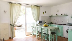 A kitchen with a dining area, a washing machine, and a TV. - Relais Gea (Massa Lubrense)