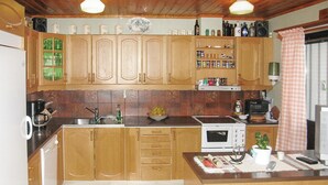 A kitchen with wooden cabinets, a microwave, a coffee maker, and various kitchen appliances. - 3 bedroom cozy home in Vimmerby (Vimmerby)