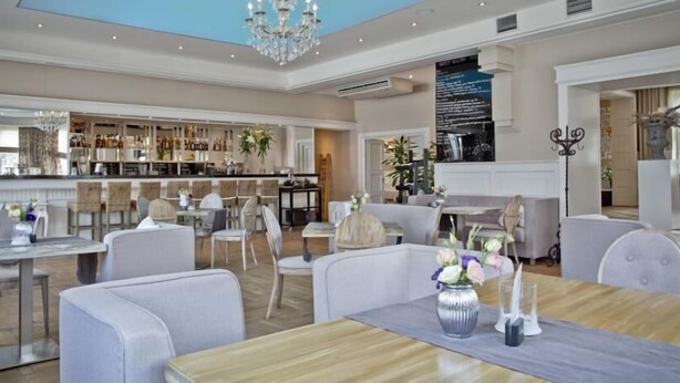 A spacious hotel lobby with a bar area, seating arrangements, and a chandelier. - Hotel Wodnik (Wroclaw)