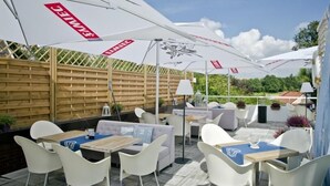 An outdoor patio with white furniture, umbrellas, and a wooden fence. - Hotel Wodnik (Wroclaw)