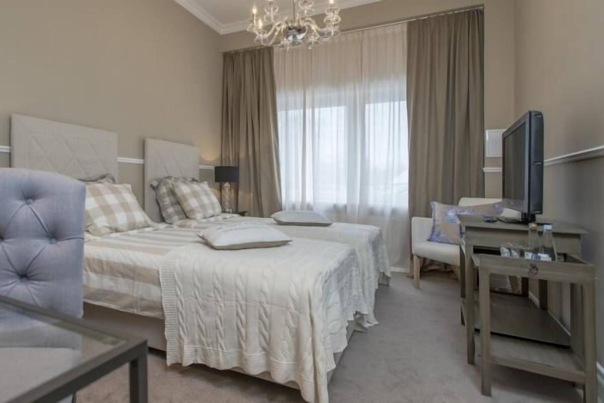 A hotel room with a large bed, a seating area with a chair, a television, and a desk.