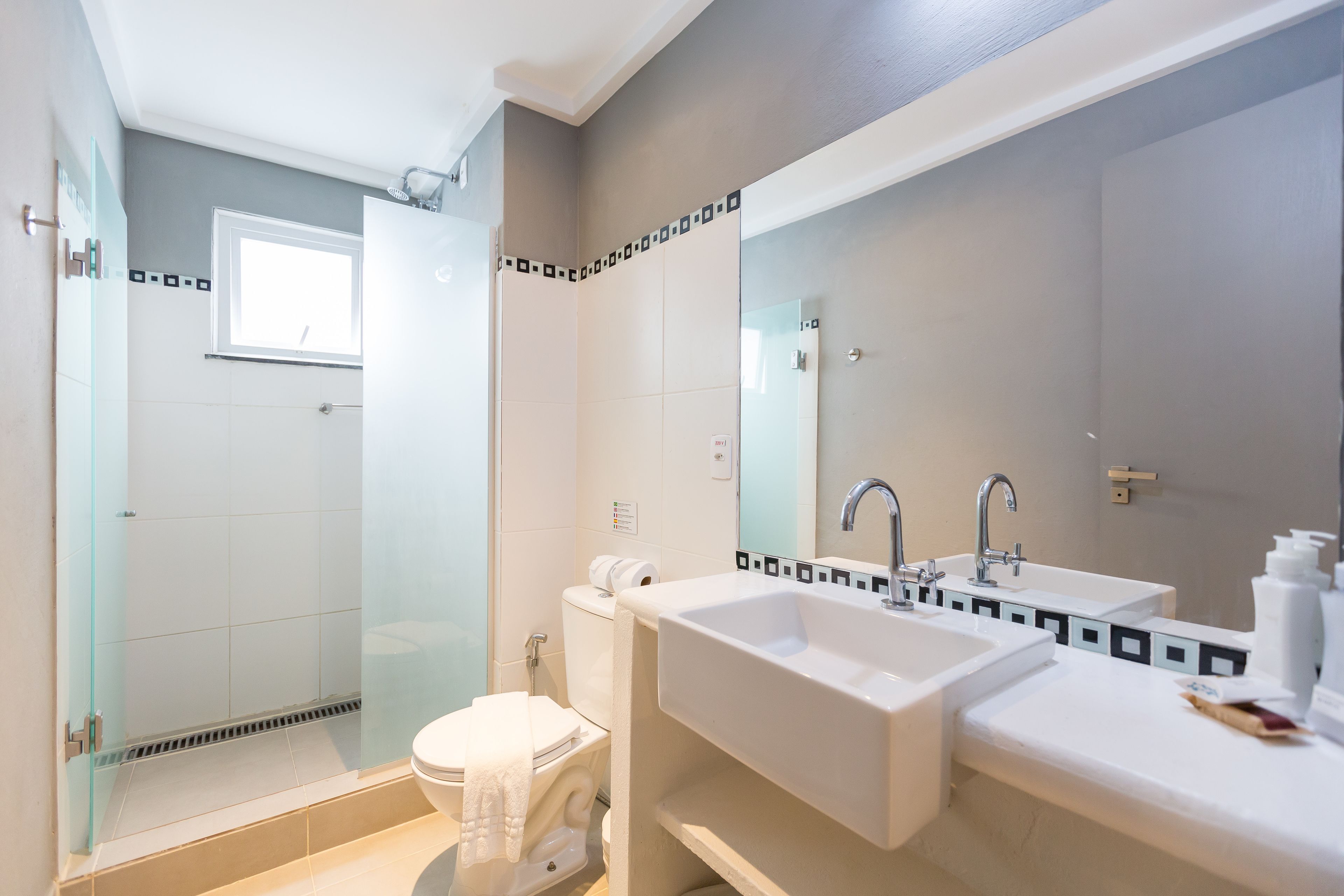 A modern bathroom with a glass-enclosed shower, a white sink, and a large mirror.