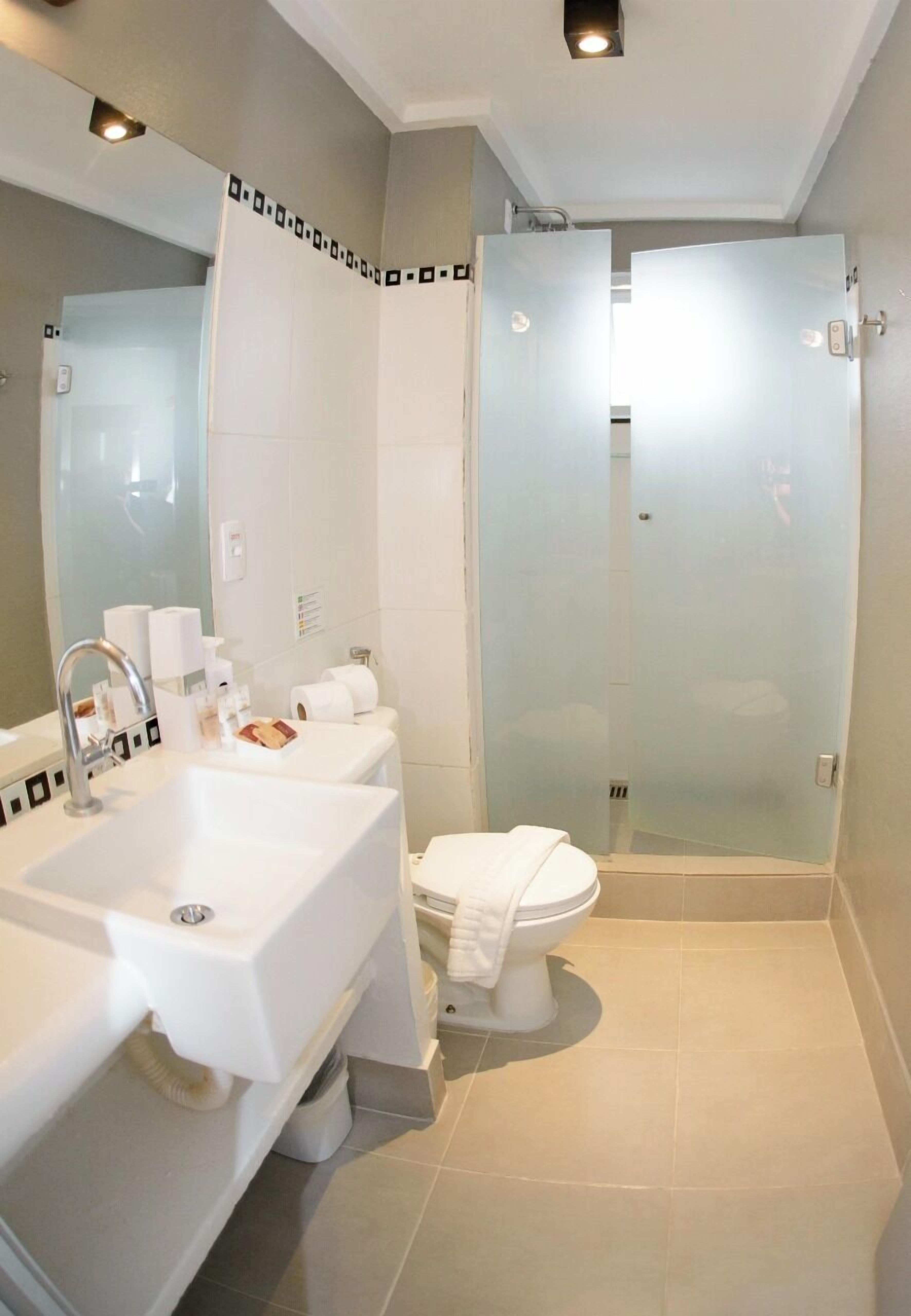 A modern bathroom with a large sink, toilet, and a glass-enclosed shower.
