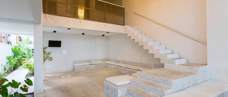 A modern interior with a stone staircase, a mezzanine level, and a minimalist design.