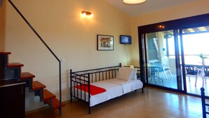 Un dormitorio con cama, una escalera, un televisor y vistas al exterior.