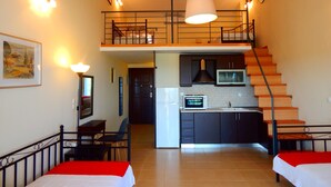 Una habitación de hotel compacta con kitchenette, una escalera y dos camas.