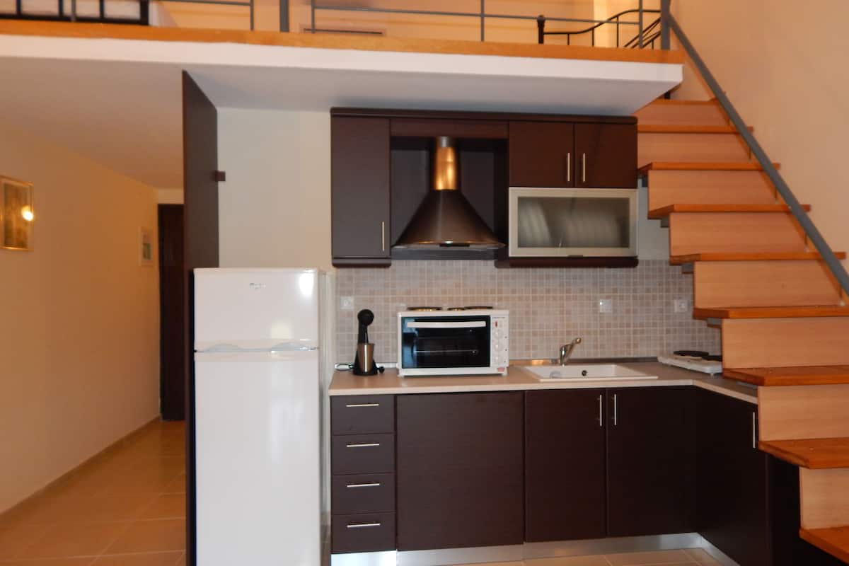 A modern kitchen with dark cabinets, a white refrigerator, a microwave, and a toaster.