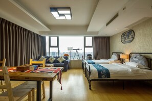 A hotel room with two beds, a sofa, a table with a Union Jack tablecloth, and a city view through large windows. - Chengdu Morpheus City Service Apartment (Chengdu)