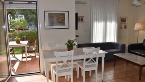 A living room with a dining area, a black sofa, and a table with chairs.