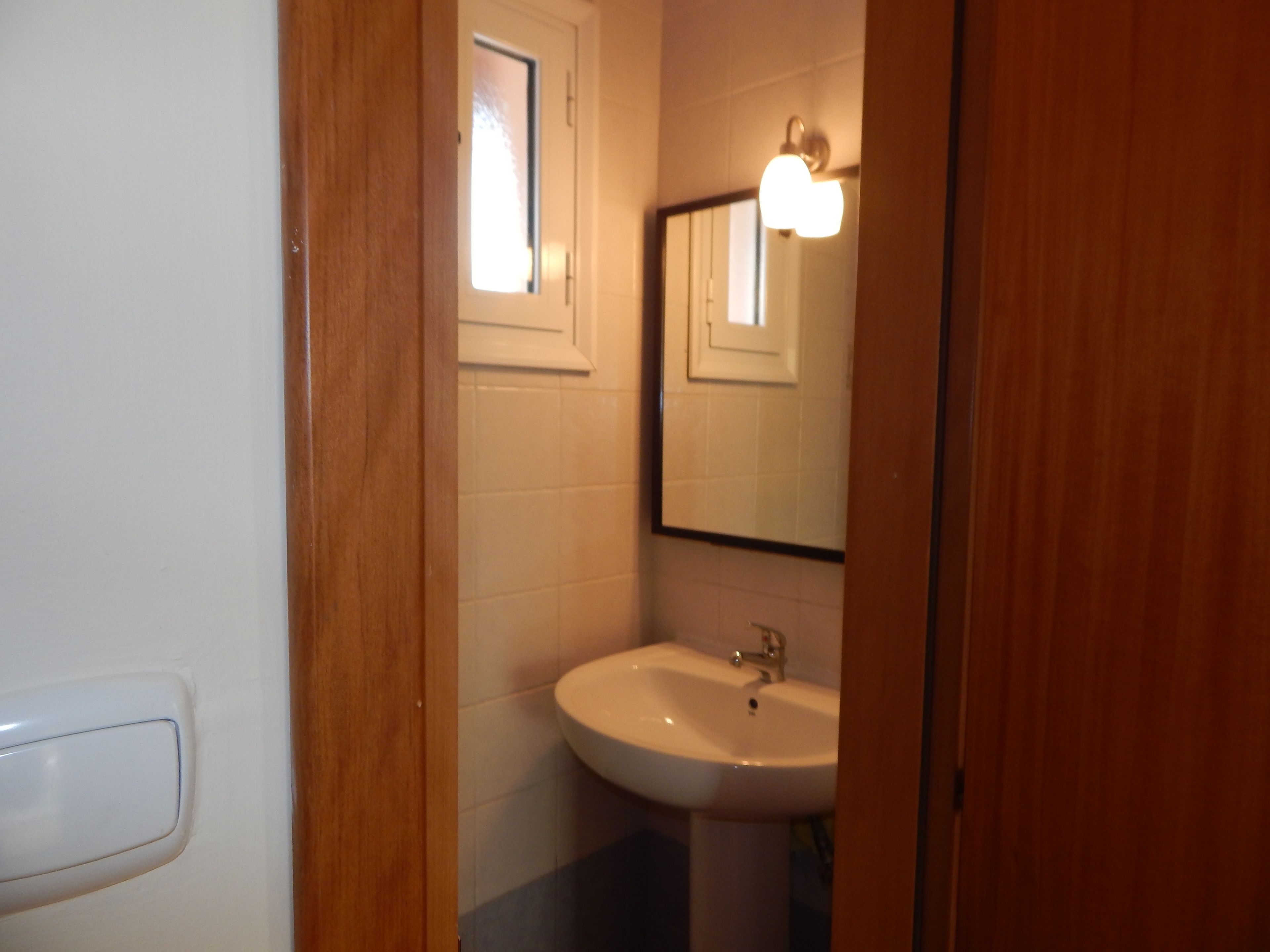 A bathroom with a white sink, a mirror, and a window.