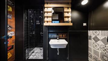 A modern bathroom with a black and white patterned floor, a white sink, and a mirror above it.