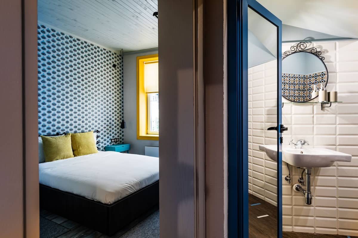 A bedroom with a bed, a nightstand, and a window.