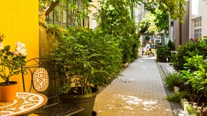 Un estrecho callejón con plantas en macetas y un banco de azulejos a la izquierda.