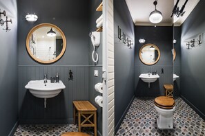 Un baño moderno con un espejo grande, dos lavamanos, un inodoro y un taburete de madera.
