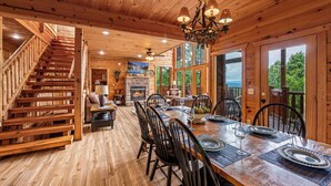 Un interno in legno con zona pranzo, scala e ampie finestre.