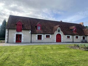 Un bâtiment traditionnel à la façade symétrique, doté de plusieurs portes rouges et d’une entrée centrale.