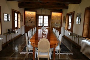 A long wooden dining table with white chairs, flanked by shelves with decorative plates, in a room with wooden beams and large windows. - Large spacious and relaxing house with  pool, tennis and pond - up  to 16p: Deer (Monthou-sur-Cher)
