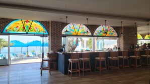 Un restaurante con zona de bar, amplios ventanales con vidrieras de colores y vistas al exterior.