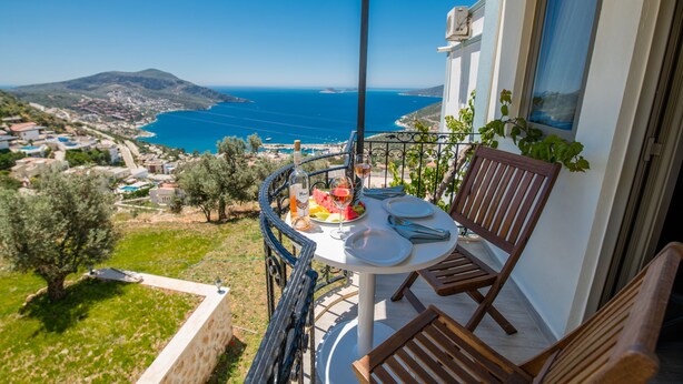 Un balcón con una mesa para dos, con vistas a la costa y una montaña al fondo.