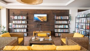 Una sala de estar con muebles de mimbre, un televisor y estanterías llenas de libros.