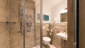 A modern bathroom with a glass-enclosed shower, a toilet, and a sink.