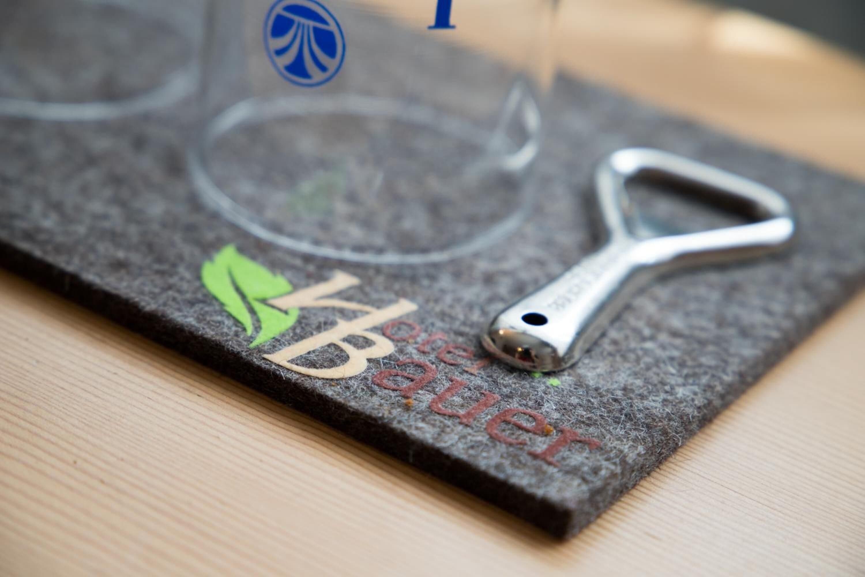 A felt coaster with a metal bottle opener and a logo.
