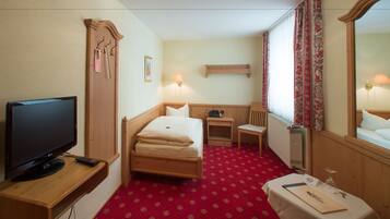 Ein Hotelzimmer mit einem Bett, einem Schreibtisch, einem Sessel, einem Fernseher und einem Spiegel.
