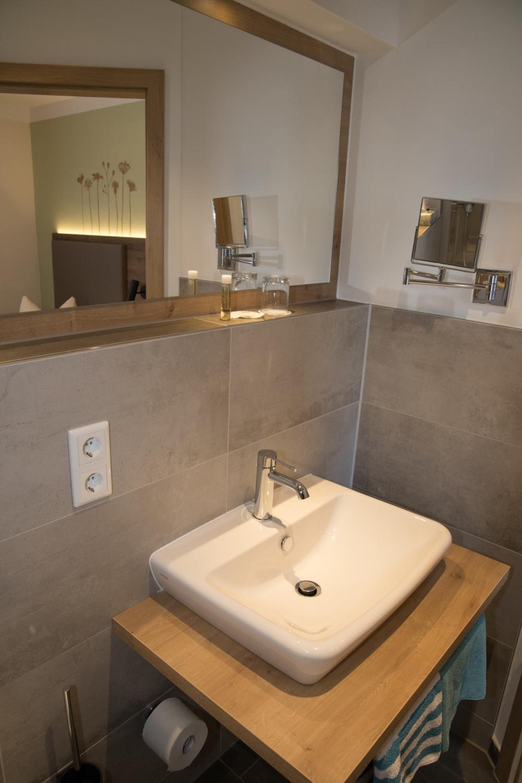 Un baño moderno con un lavamanos blanco, encimera de madera y un espejo encima.